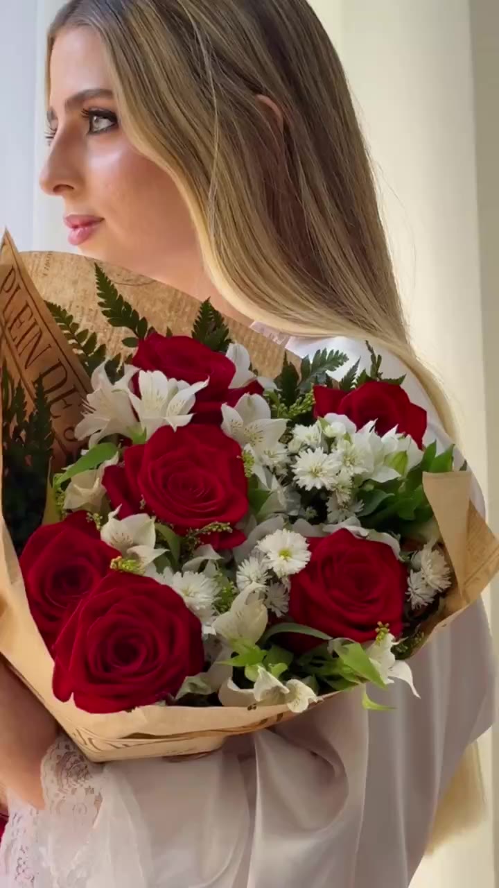 Noiva segurando um buquê de rosas vermelhas junto à janela